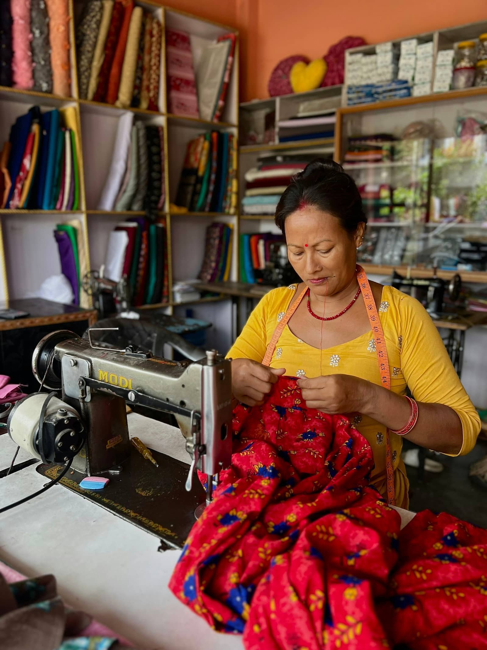 A woman stitching fabric on a sewing machine in a tailoring workshop