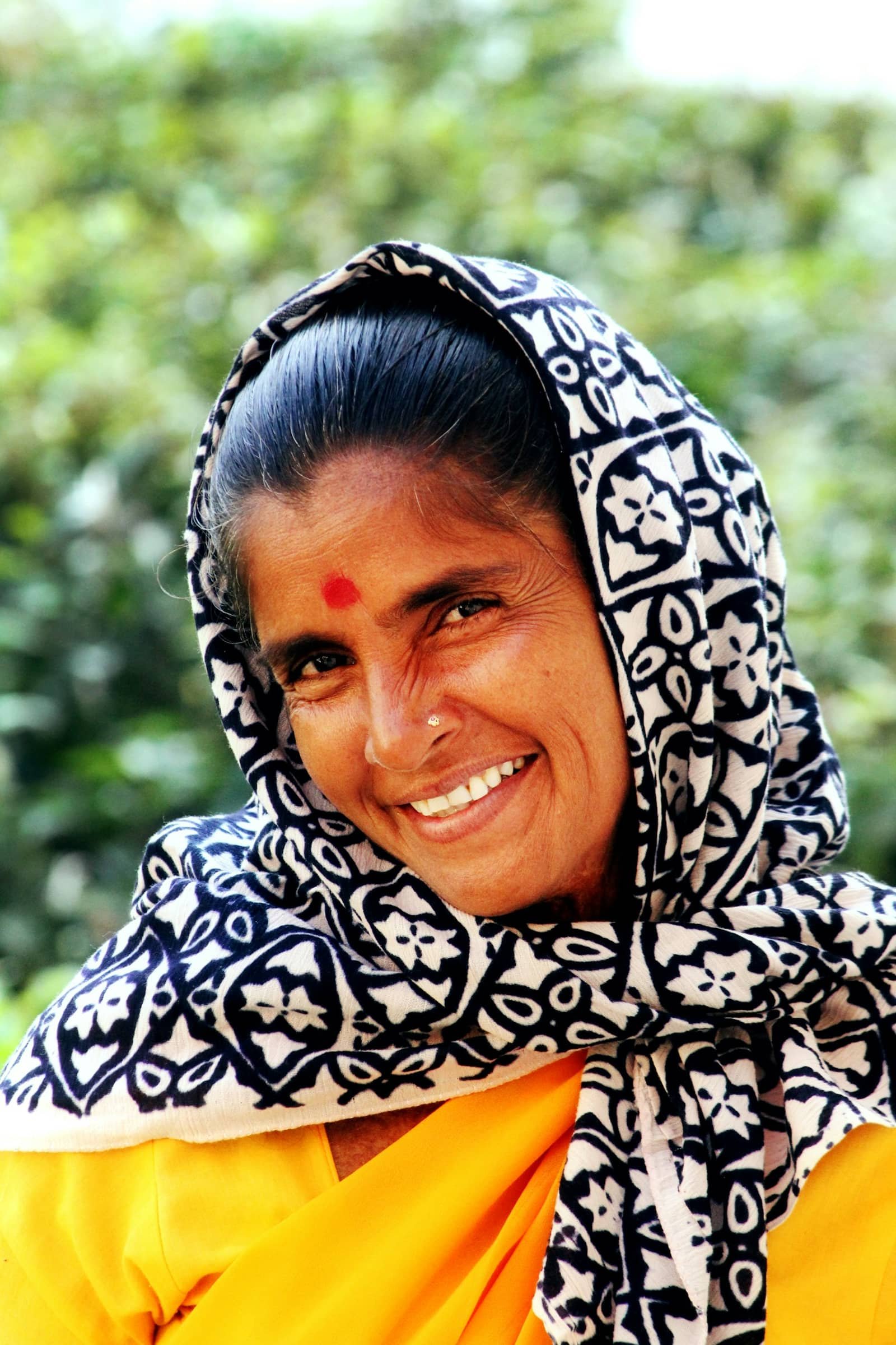 A smiling elderly woman in a patterned headscarf
